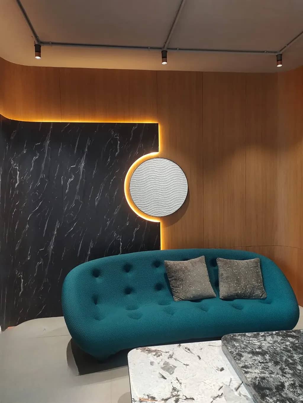 Teal sofa against black marble and wood veneer panelling